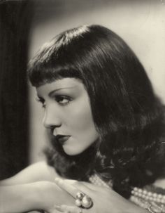 black and white photograph of a woman with her hand on her shoulder, looking off to the side