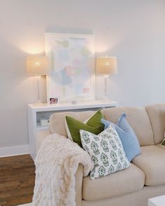 a living room with a white couch and two lamps on the side tables in front of it