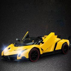 a yellow and black sports car is on the road with its doors open, it's light up