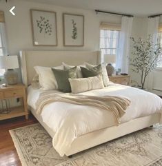 a large bed sitting in a bedroom on top of a hard wood floor next to two windows