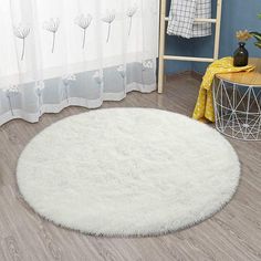 a white round rug on the floor in a room with blue walls and wooden floors