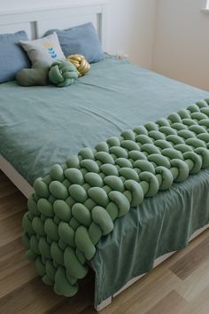 a bed made up with green pebbles on the headboard and foot board, along with a stuffed animal