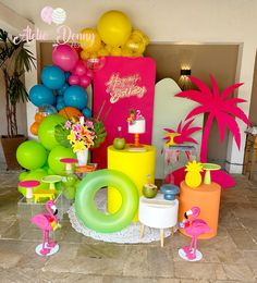 there are many balloons and decorations on the floor in front of this party table with flamingos