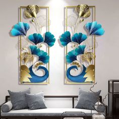 two blue and gold flowers are hanging on the wall above a couch in a living room