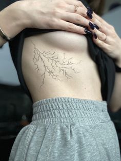 a woman's lower back tattoo with branches on her stomach and the upper part of her body visible