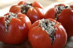 four tomatoes with rice on them sitting on a cutting board