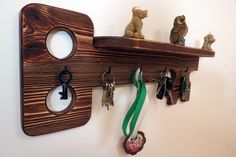 a wooden shelf with key hooks and keys hanging on it's sides, along with several small animal figurines