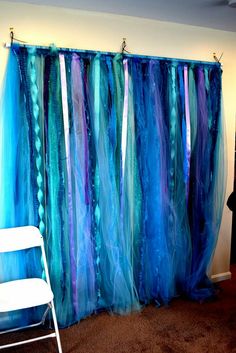 a chair sitting in front of a curtain with blue and purple streamers on it