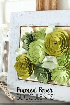 some paper flowers are in a white frame