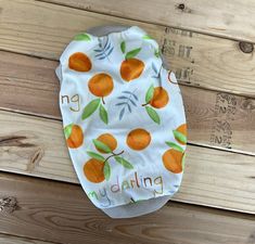 a cloth diaper with oranges on it sitting on a wooden floor next to wood planks