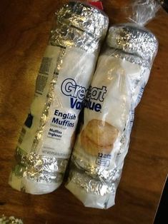 two bags of bread sitting on top of a wooden table next to a bag of popcorn