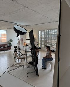 a woman sitting on a stool in front of a camera set up for a photo shoot