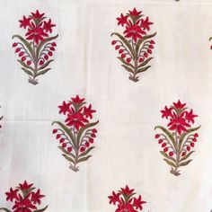 red flowers on white fabric with green stems and leaves in the center, as well as other designs