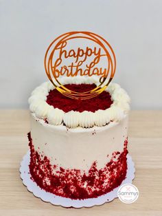 a red and white cake sitting on top of a wooden table next to a sign that says happy birthday