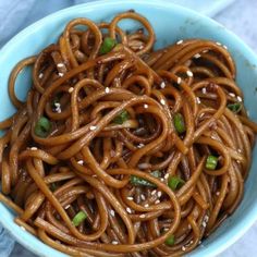 a blue bowl filled with noodles on top of a white table cloth next to chopsticks