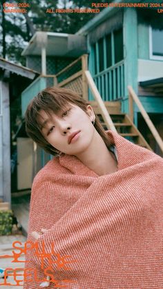 a young man wrapped up in a blanket on the cover of a magazine with stairs behind him