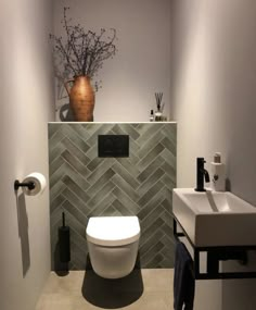 a white toilet sitting next to a bathroom sink under a brown vase on top of a counter