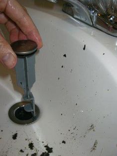 a person holding a plunger in a sink filled with dirty water and black stuff