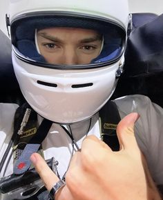 a man wearing a white helmet and pointing at the camera with his index finger in front of him