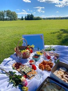 a picnic table with food on it in the middle of a grassy field and blue sky