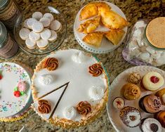 a table topped with cakes and desserts on top of a counter covered in frosting