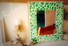 a green and white mosaic tile mirror next to a candle