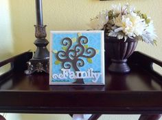 a wooden table topped with a vase filled with white flowers and a sign that says family