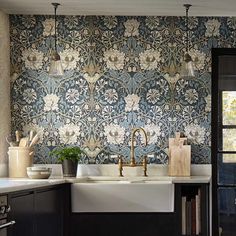 the kitchen is decorated with blue and white floral wallpaper, along with brass faucets