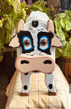 a cow statue sitting on top of a table next to some potted planters