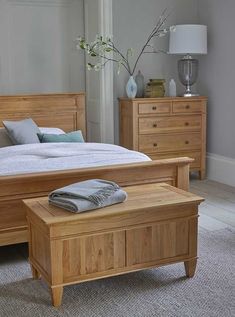 a wooden bed sitting next to a dresser with drawers on each side and a lamp on top of it