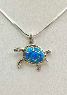 a turtle pendant with blue opal inlays on it's back end