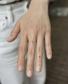 a woman's hand with a small star tattoo on it, and a tiny cross in the middle