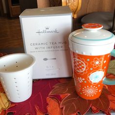 a ceramic tea pot and cup sitting on top of a table next to a box