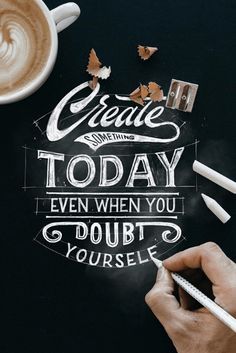 a person writing on a chalkboard next to a cup of coffee and pencils