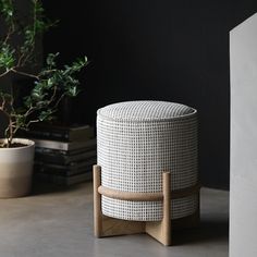 a white stool sitting on top of a table next to a potted plant and books