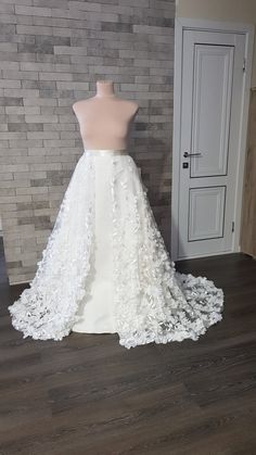 a white wedding dress on display in front of a brick wall and wooden flooring