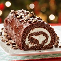 a chocolate roll on a plate with christmas lights in the background