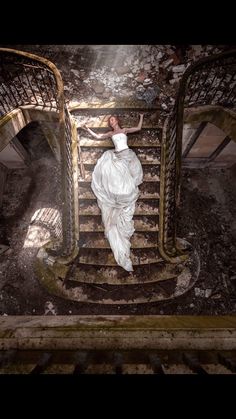 a woman in a white dress is walking down some stairs