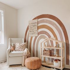 a living room with a white chair and a book shelf in front of a rainbow wall