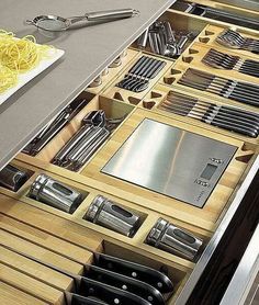 an assortment of kitchen utensils and knives in a drawer on a counter top