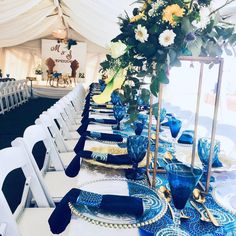 a table set up with blue and white plates, place settings and flowers in vases