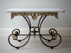 a marble topped table sitting on top of a tile floor next to a wall with white walls