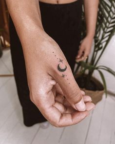 a person's hand with a small crescent and star tattoo on the middle finger