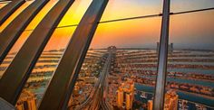 an aerial view of the city from inside a building at sunset or sunrise, looking down on buildings and water