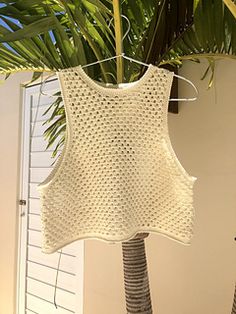 a white knitted top hanging from a palm tree