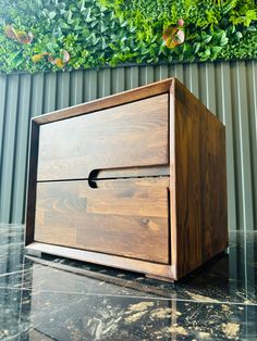 a wooden box sitting on top of a black marble floor next to a green wall