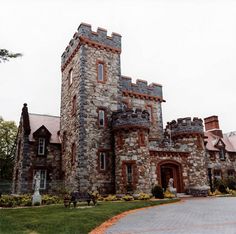 an old castle like building is shown in the middle of a driveway and grass area