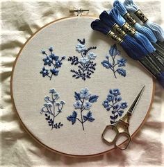 the embroidery is being worked on with blue thread and scissors, along with other items