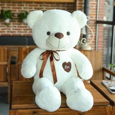 a white teddy bear sitting on top of a wooden table