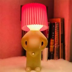 an elephant lamp with a pink shade on it's head in front of a bookshelf